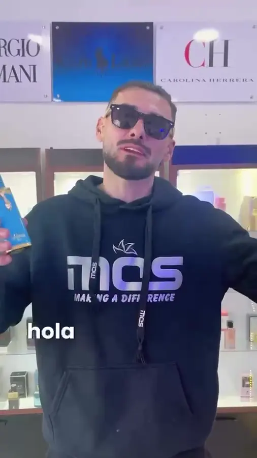 Pablo mostrando un perfume azul dentro de la tienda Esencia Moderna